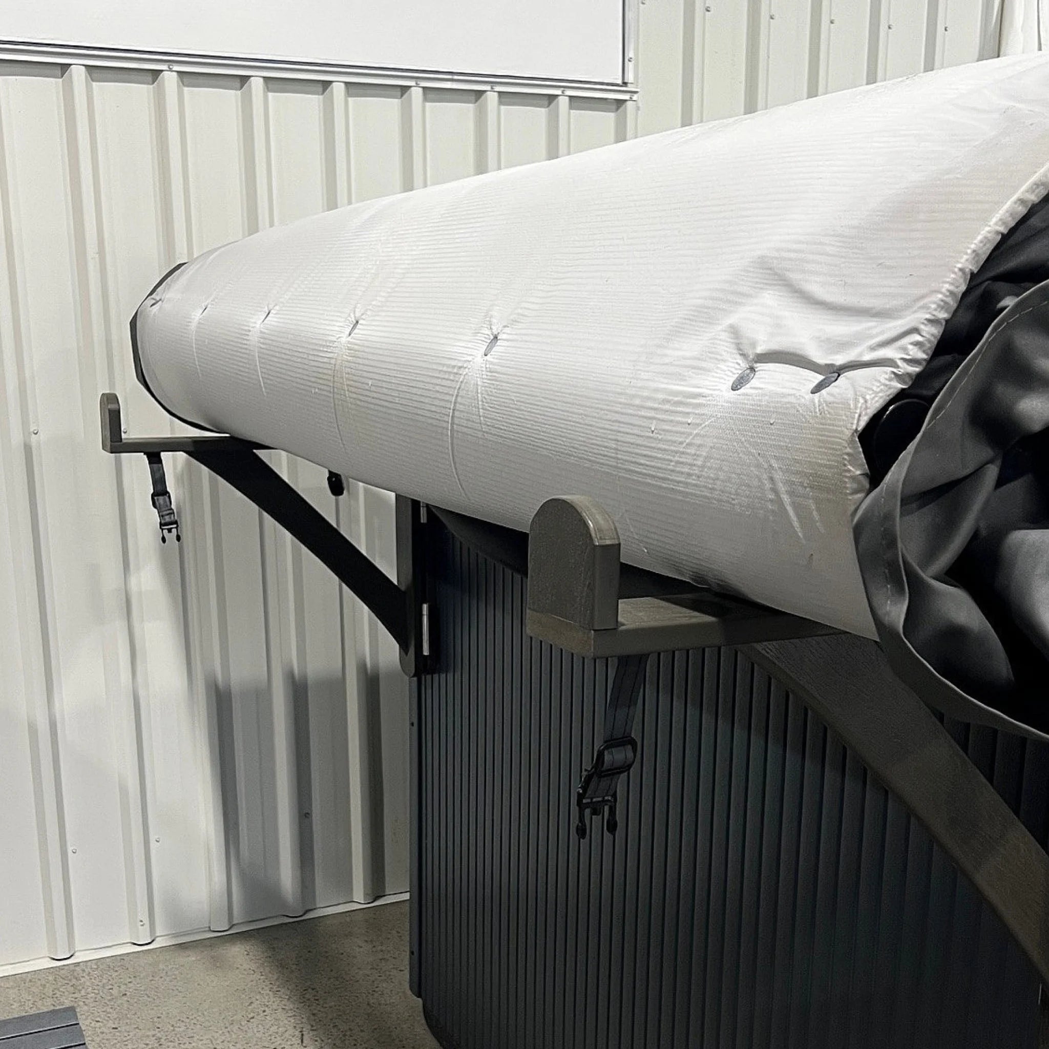 Rolling spa cover bracket cabinet mount, shown with cover rolled onto brackets.